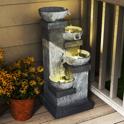 charcoal bowl tower fountain lit warm on a porch beside terracotta pot of orange flowers