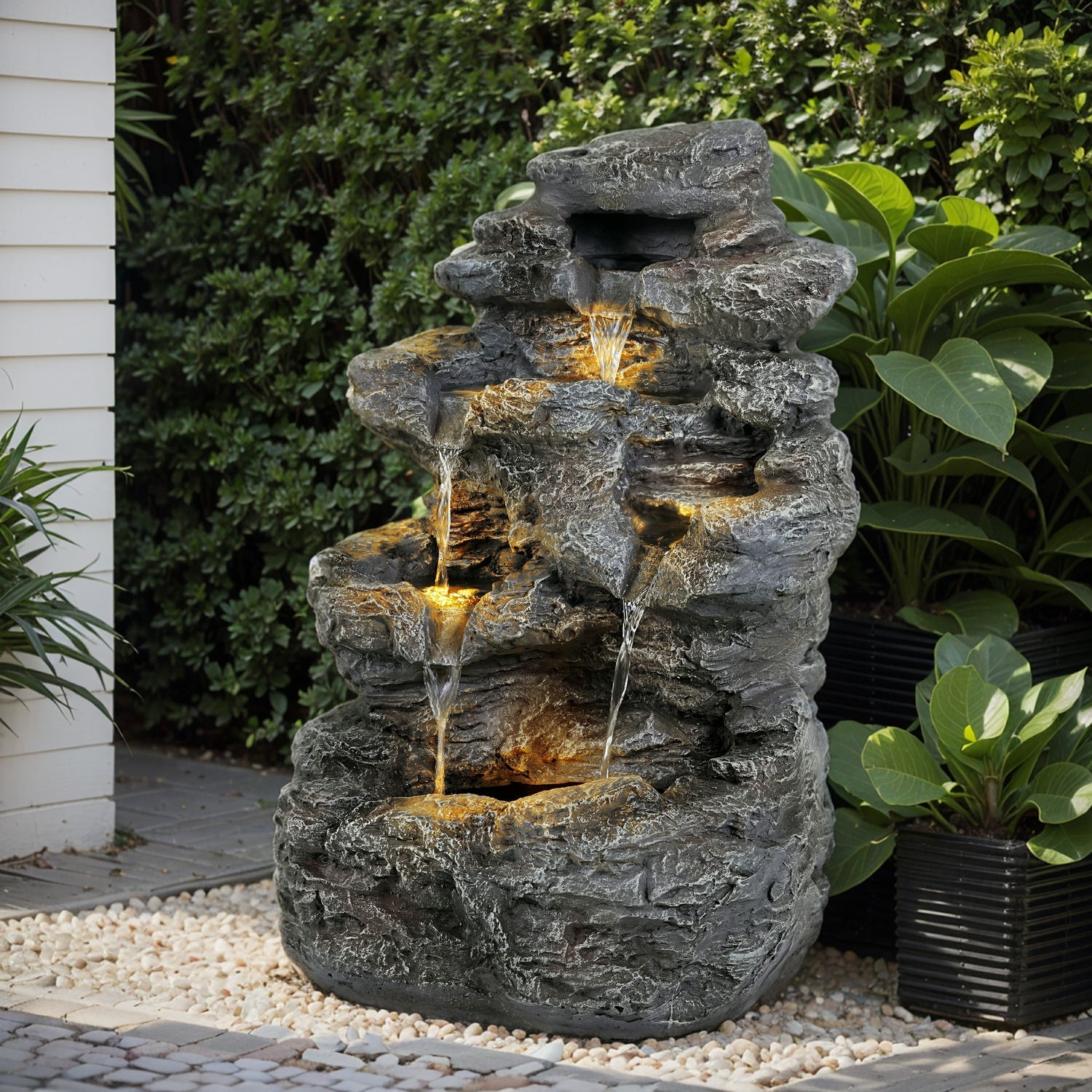 concrete rock ledge fountain lit warm among tropical plants and gravel