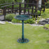 fleur-de-lis green verdigris pedestal bird bath on a garden lawn beside a wooden footbridge