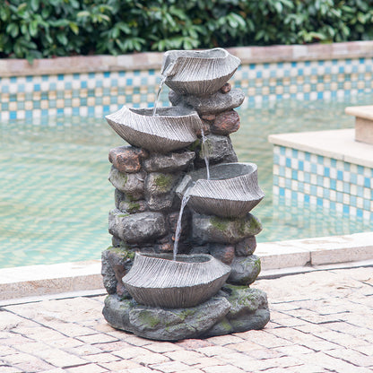 fluted basin rock fountain beside a swimming pool on paving