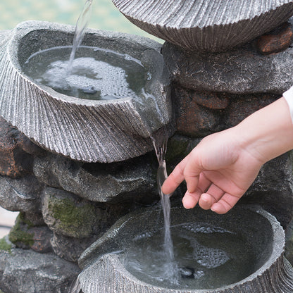 hand touching the cascading water flow of the fluted basin rock fountain
