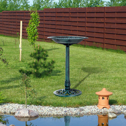 green verdigris pedestal bird bath in a landscaped backyard near a small garden pond