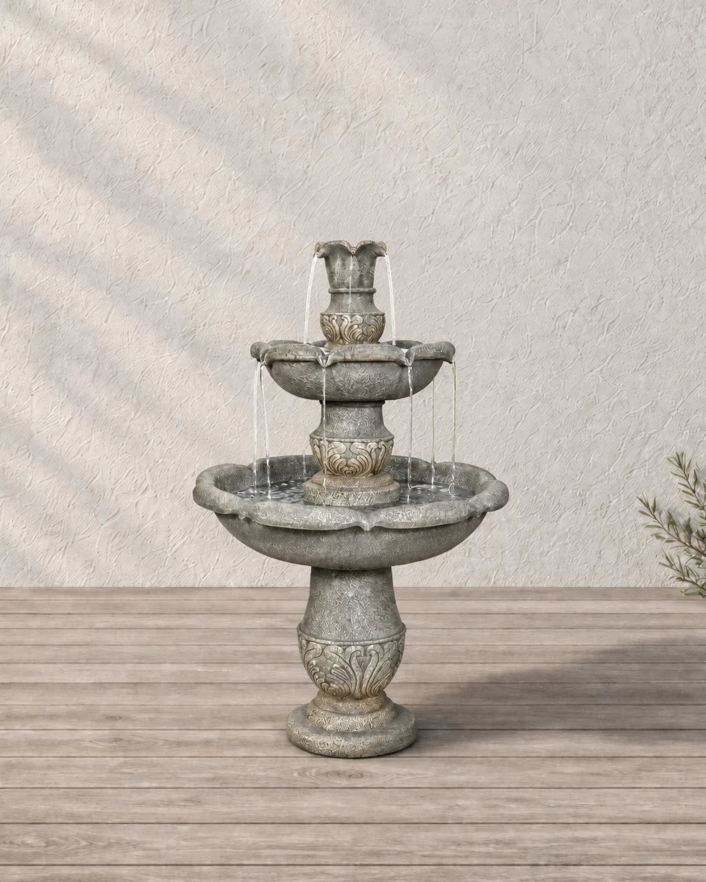 Carved two tier concrete outdoor water fountain running on a pale oak deck