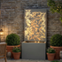 leaf wall cascade fountain glowing warm at night against brick wall
