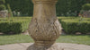 Classic tiered garden fountain with cascading water flow in a sunlit outdoor garden setting