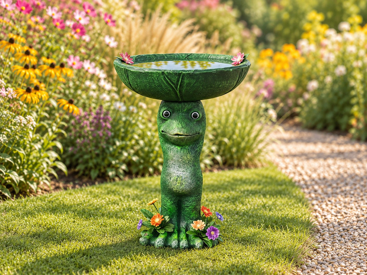 Standing frog concrete bird bath holding a lily pad basin on a lawn by a flower border