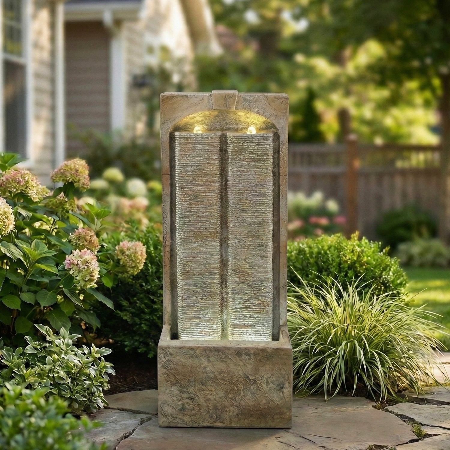 split sandstone column fountain in a garden with hydrangeas along a stone path