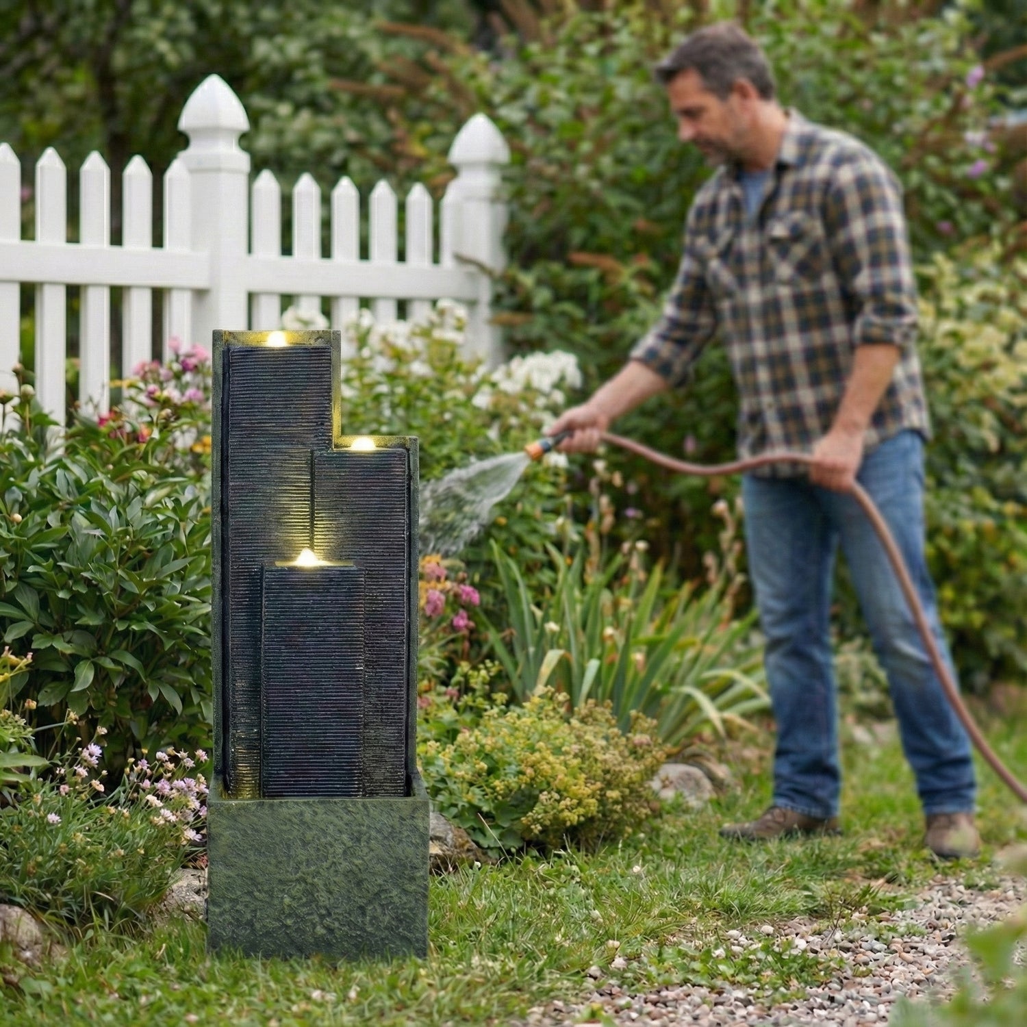 homeowner watering garden plants beside staggered cascading fountain