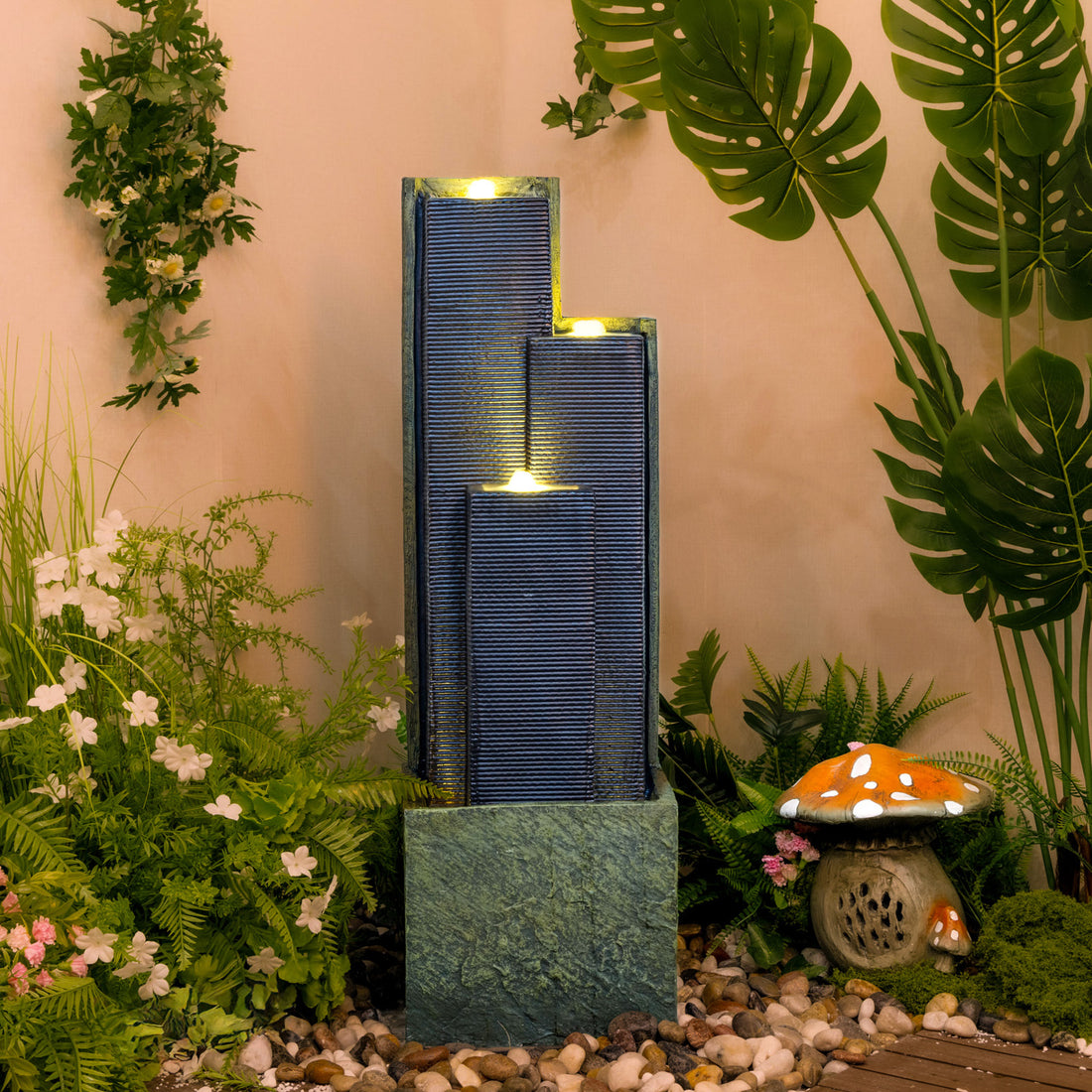 staggered dark slate column cascade fountain in a tropical garden setting with warm LED glow