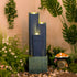 staggered dark slate column cascade fountain in a tropical garden setting with warm LED glow