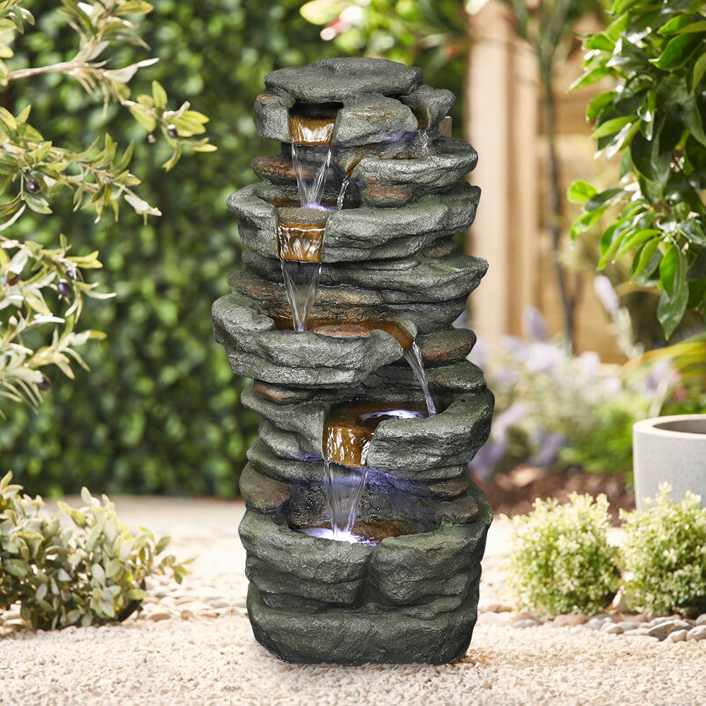 32.6"H simulation slate stone fountain adding a refreshing oasis feel to a sandy outdoor garden.