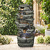 32.6"H simulation slate stone fountain adding a refreshing oasis feel to a sandy outdoor garden.
