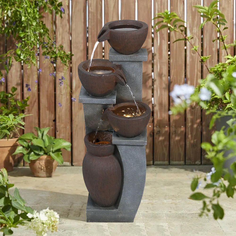 32.8"H pouring pots fountain integrated into a lush backyard garden setting.