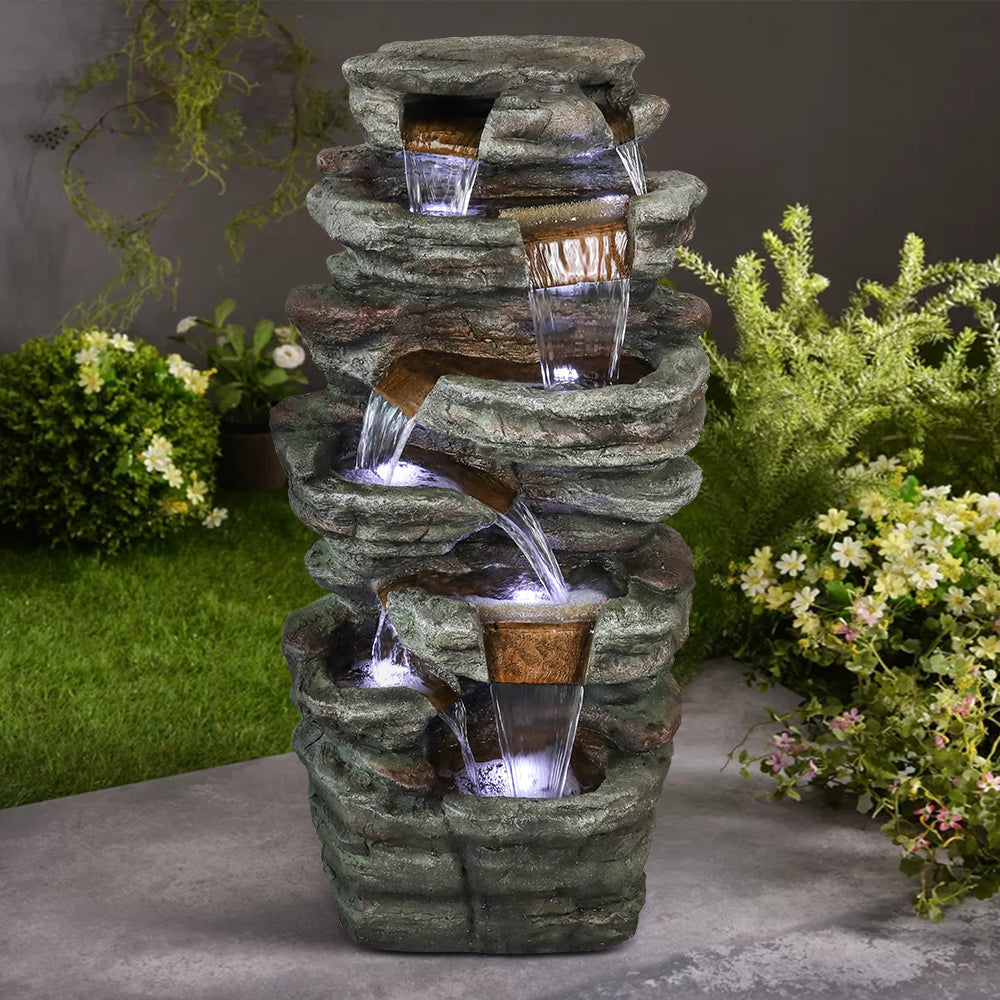 48"H 7-tier stacked shale outdoor fountain creating a peaceful focal point in a lush garden corner.