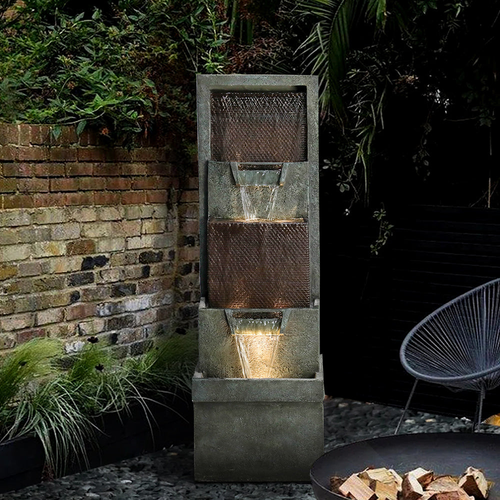 Dark gray outdoor fountain with LED lights illuminating a relaxing backyard patio at night