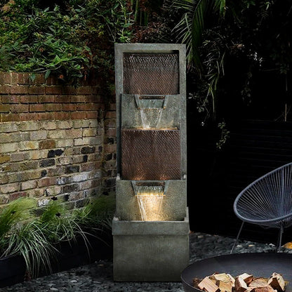 Dark gray outdoor fountain with LED lights illuminating a relaxing backyard patio at night