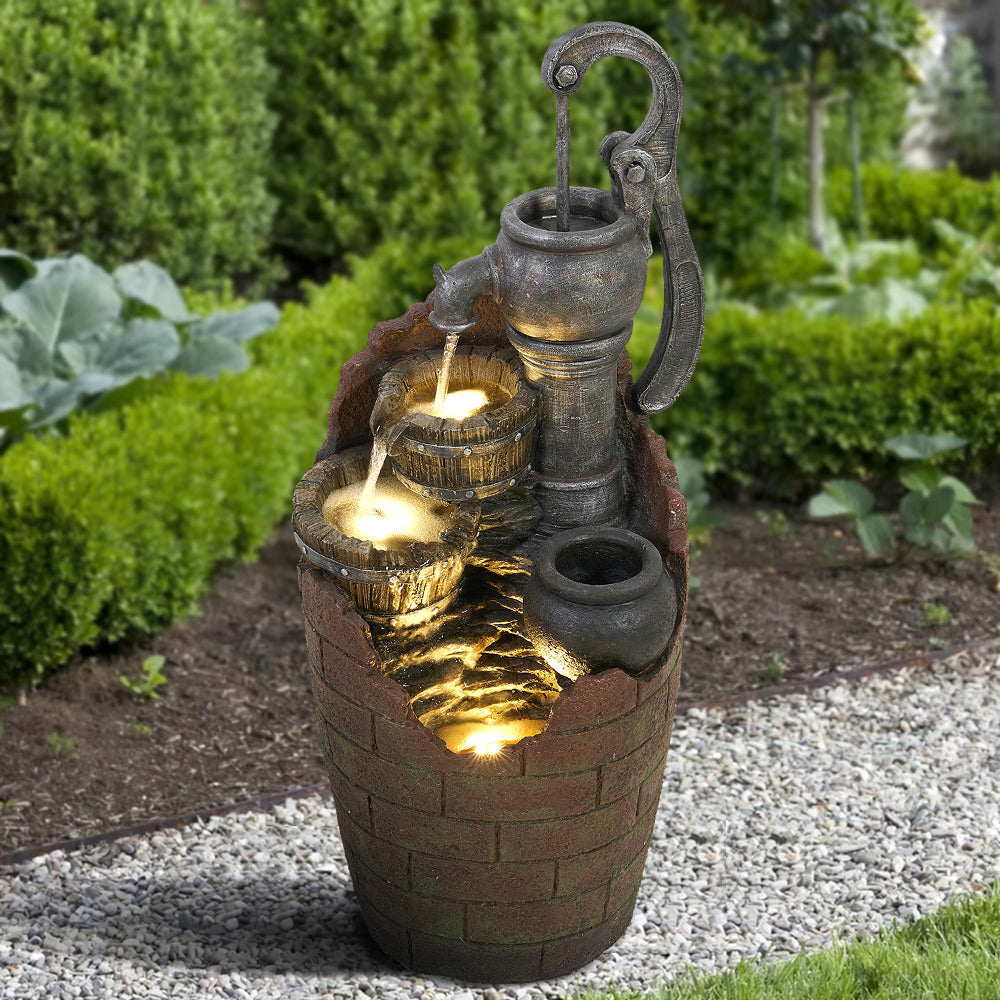 Farmhouse style wood-like barrel water feature standing on a green lawn