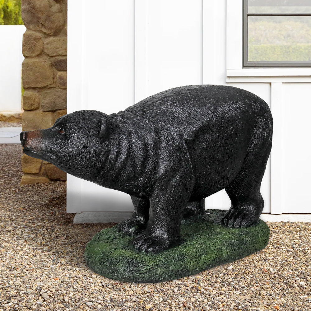 Lifelike concrete black bear sculpture nestled among colorful garden flowers