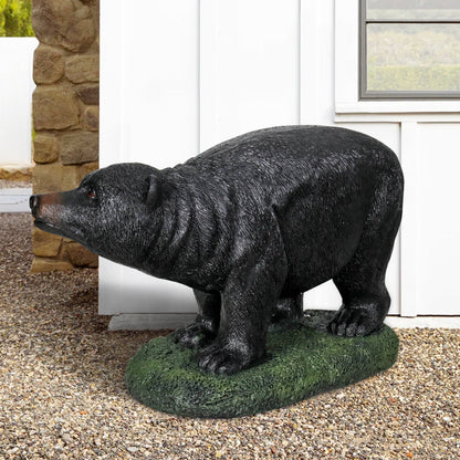 Lifelike concrete black bear sculpture nestled among colorful garden flowers