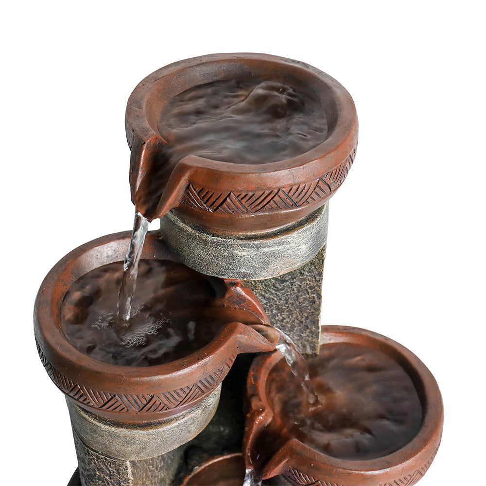 Macro view focusing on the highest tier of the active fountain with a glowing LED light and cascading water.