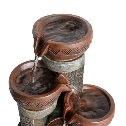 Macro view focusing on the highest tier of the active fountain with a glowing LED light and cascading water.