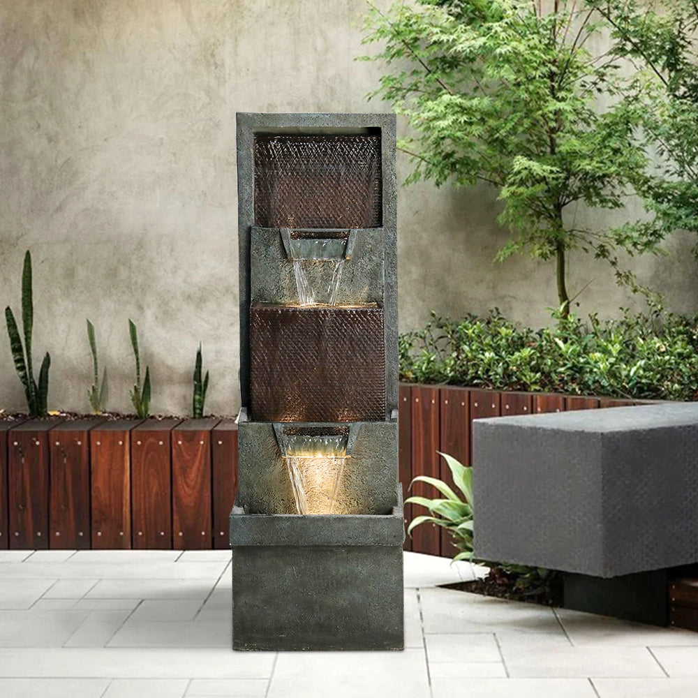 Modern dark gray cascading waterfall fountain creating a peaceful atmosphere in a lush garden