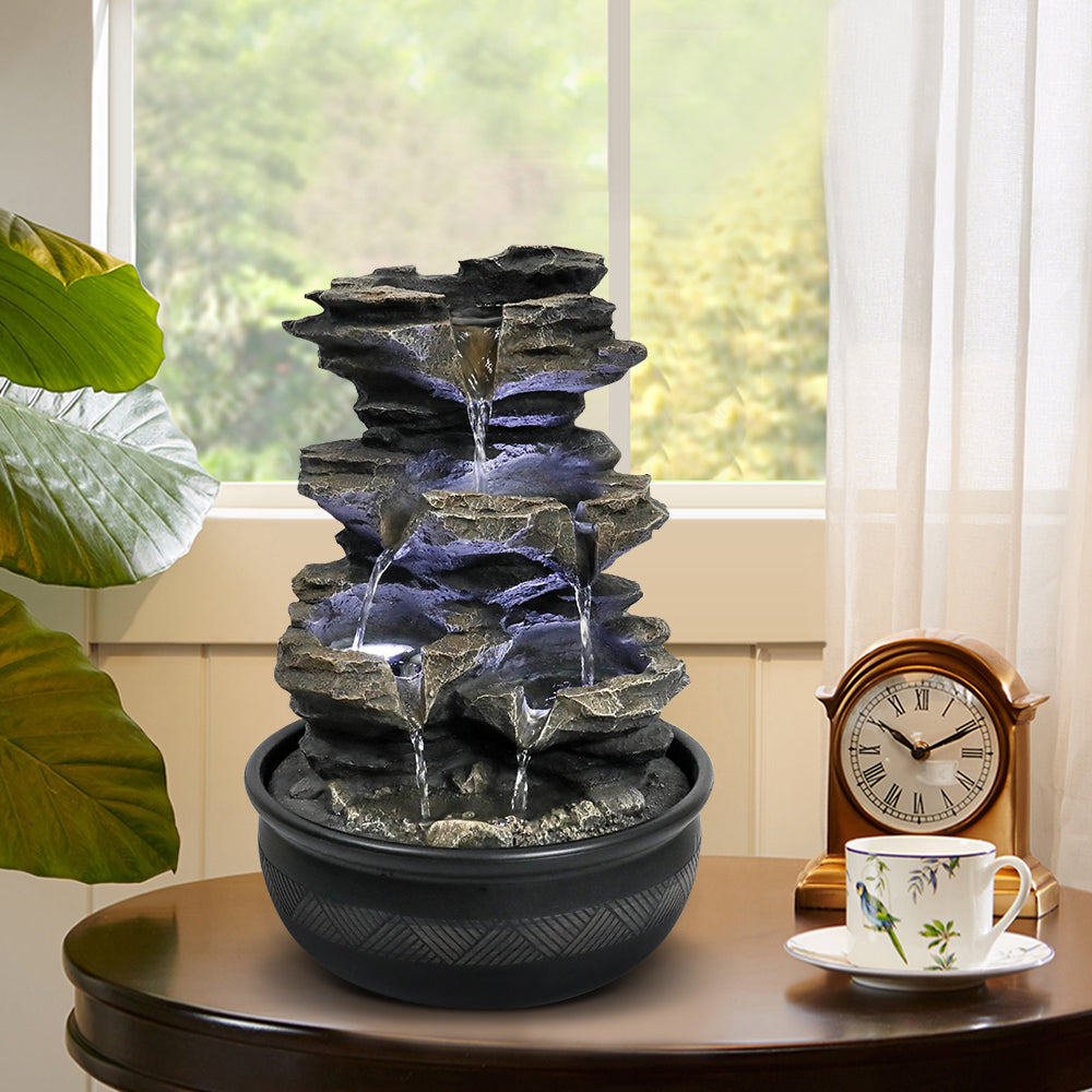 Realistic moss-coated rock indoor waterfall decorating a living room side table