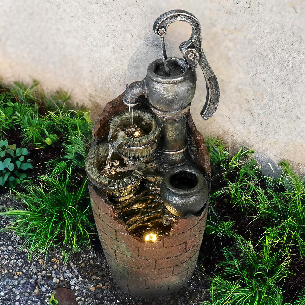 Rustic outdoor fountain with LED lights illuminating the pump and barrels at night