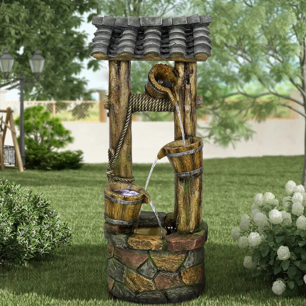 Vintage faux wood bucket water feature standing on a green lawn in the daytime